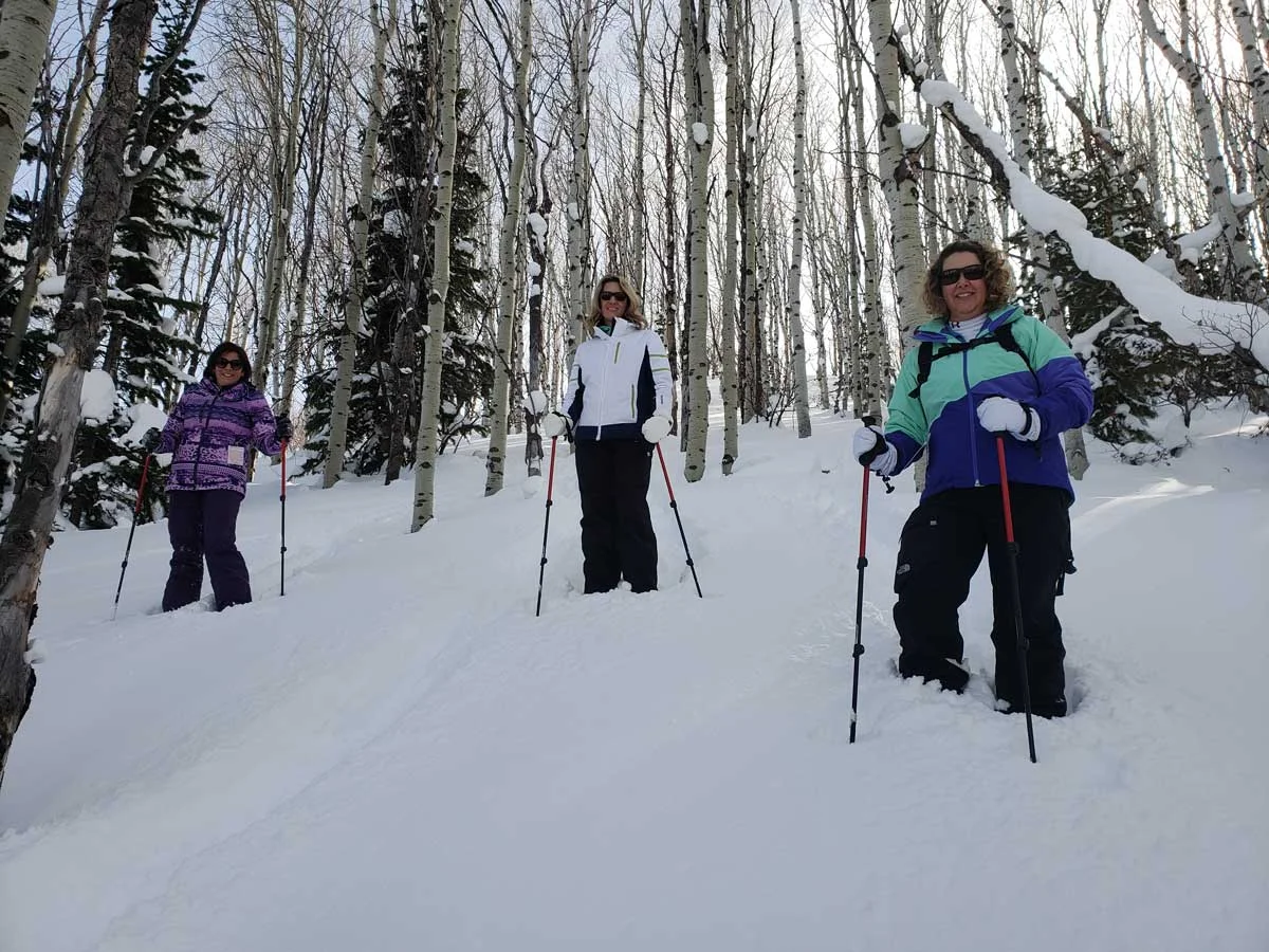3 women snowshoe powder